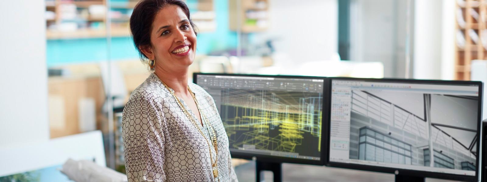 A woman sitting on a desktop workstation smiling into a camera 