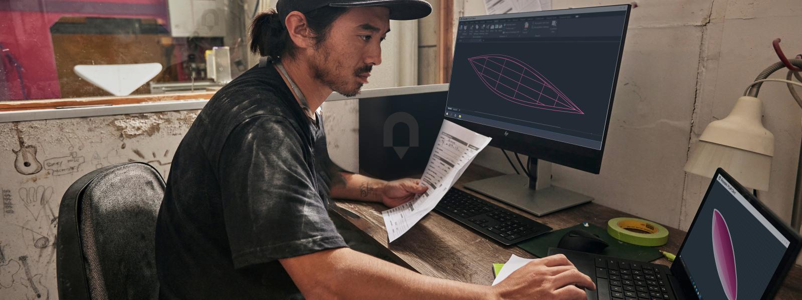 Man at computer with a laptop and screen 